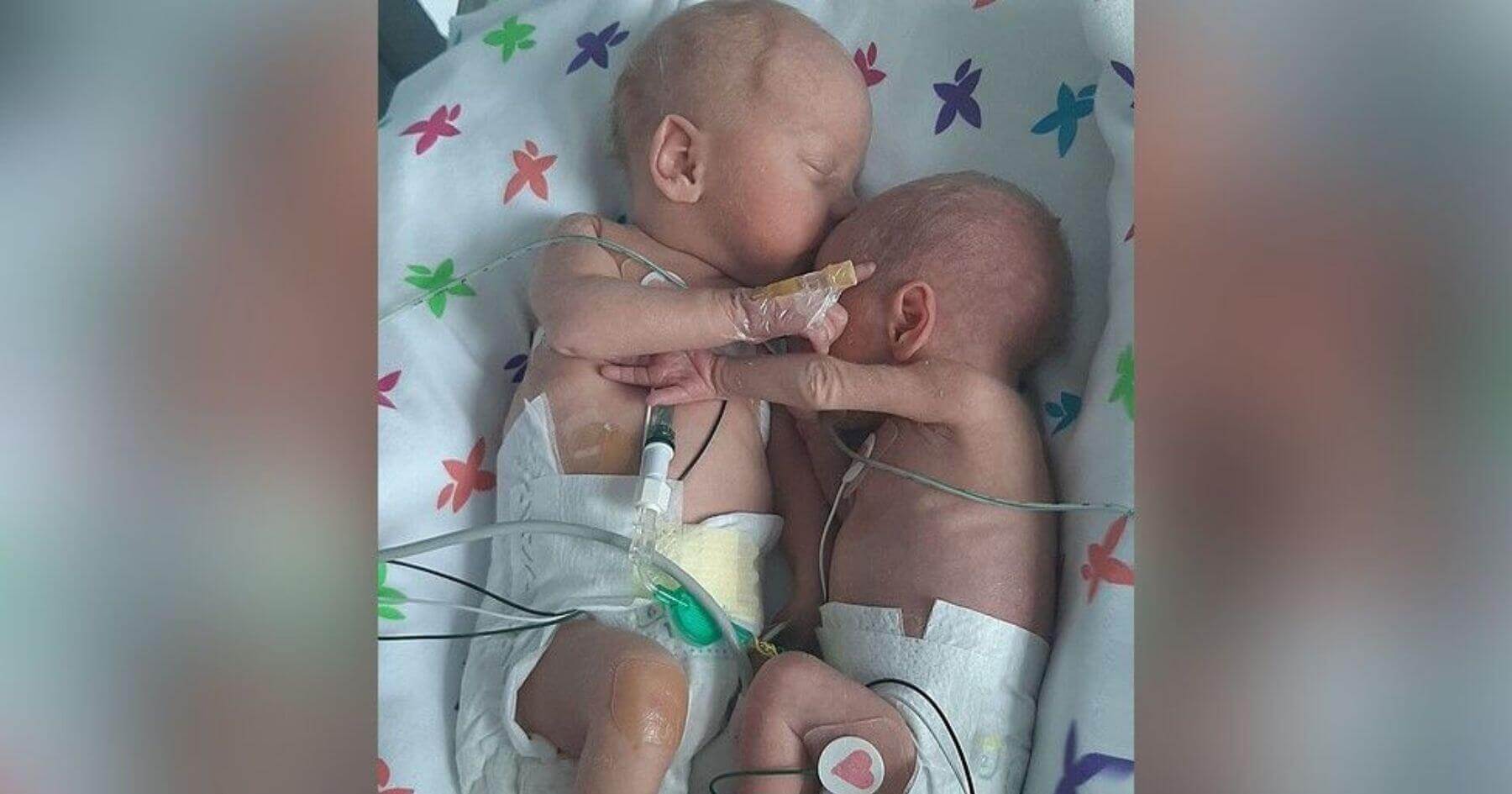 Premature twins separated at birth cuddle and hold hands